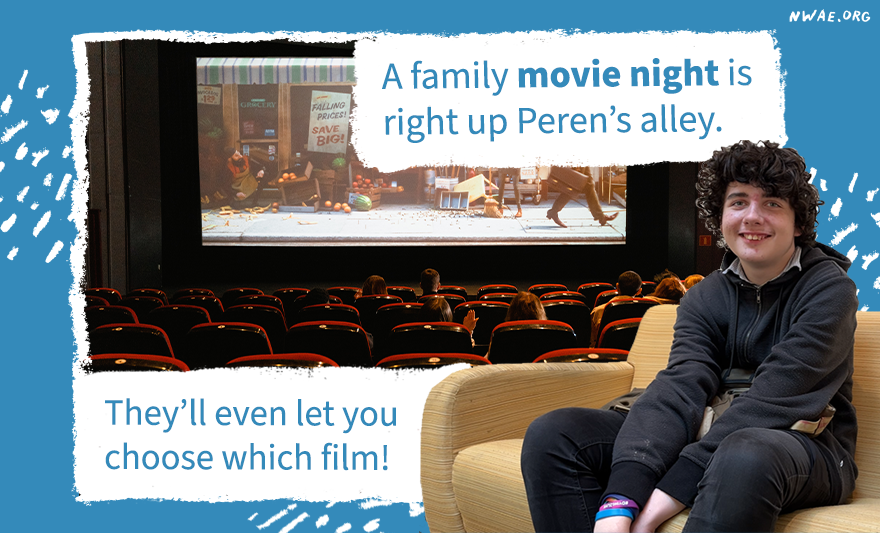 Peren sitting in a chair smiling next to a movie screen. They would love a family movie night.